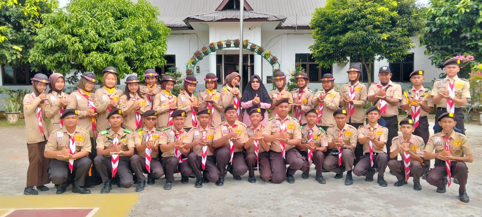 Kelompok pramuka sedang berkemah di hutan dengan seragam lengkap, sedang berdiskusi di sekitar api unggun